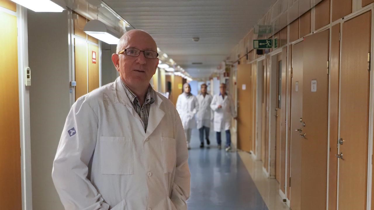 En man i labbrock som står i en korridor.