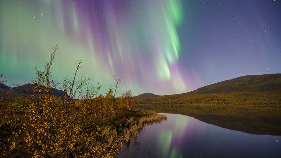 Northern lights in the sky over mountain lake landscape