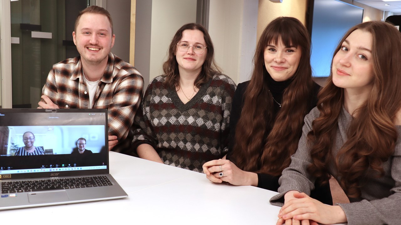 Fyra sitter på rad vid bord, två på datorskärm