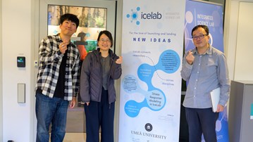 Three people stand and hold their fingers together around a banner advertising IceLab