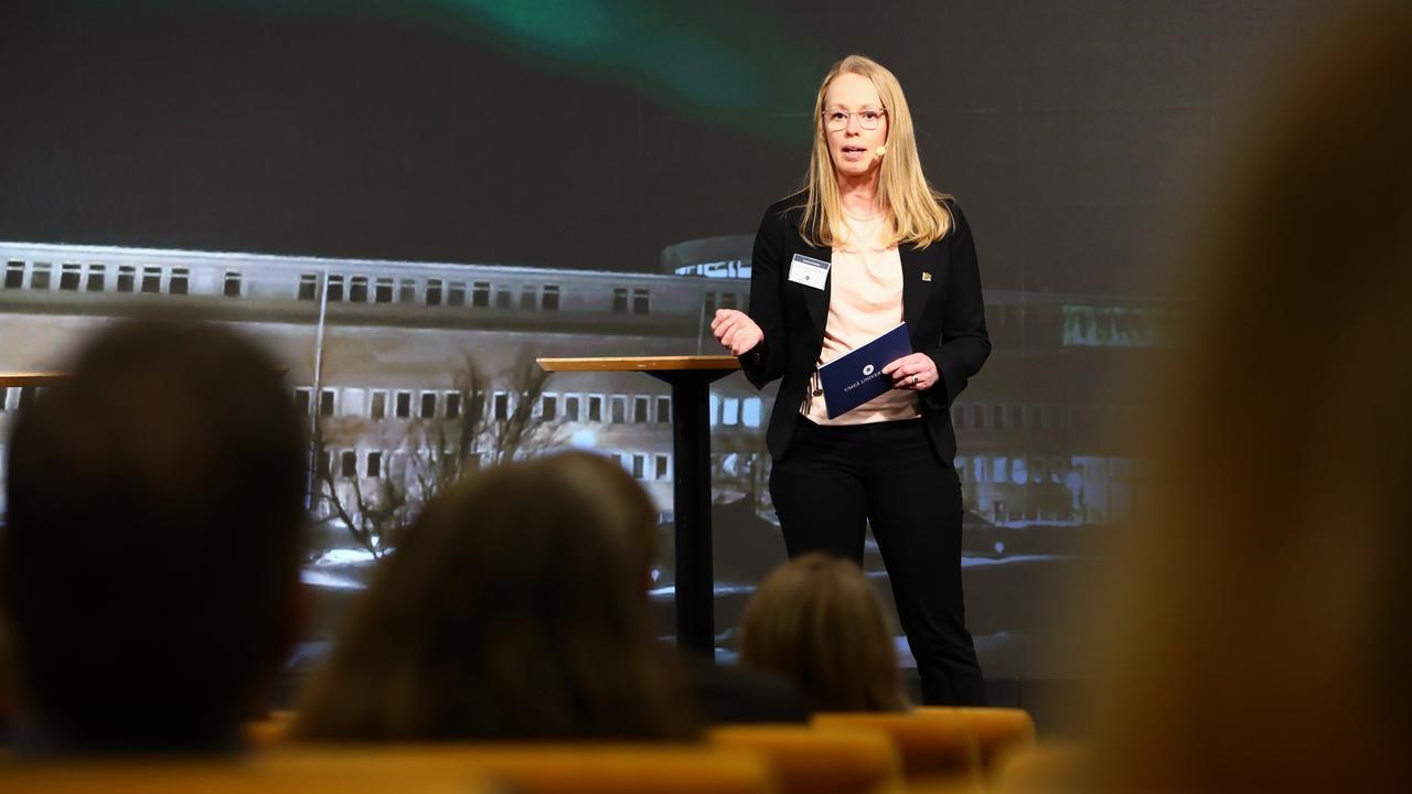 En kvinna står på ett podium framför en folkmassa.
