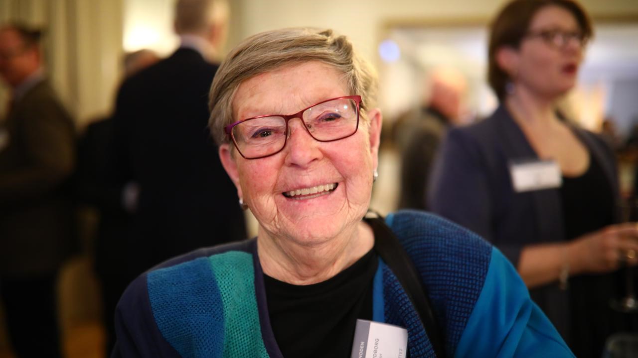 En kvinna med glasögon ler mot kameran.