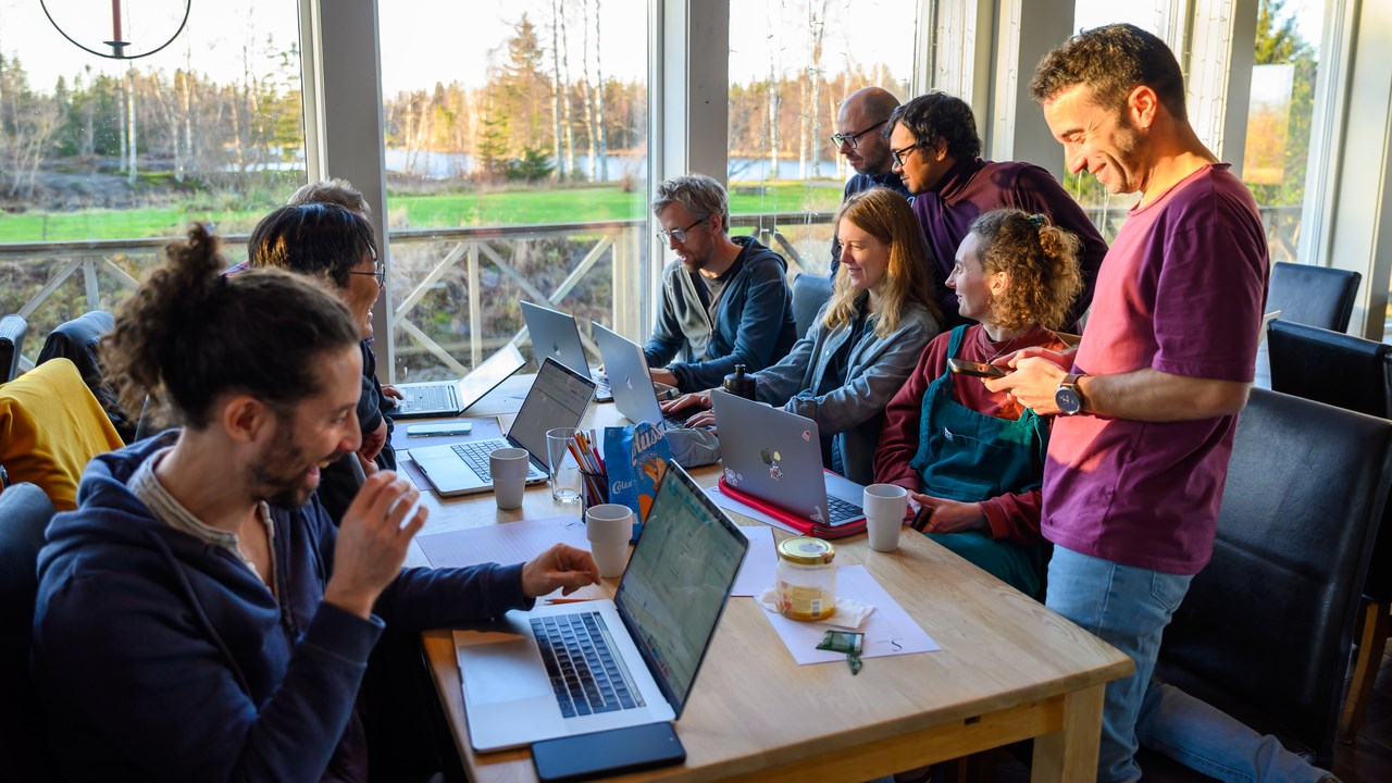 A group of people sitting at a table with laptops