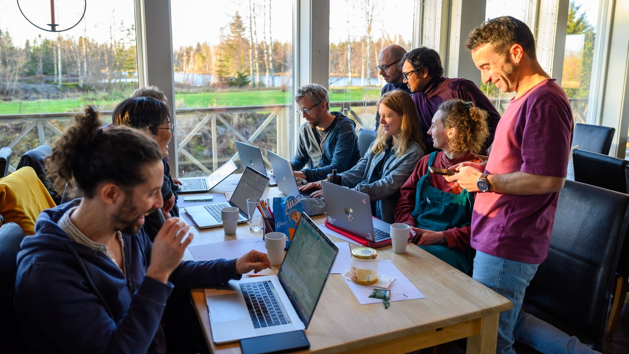 A group of people sitting at a table with laptops