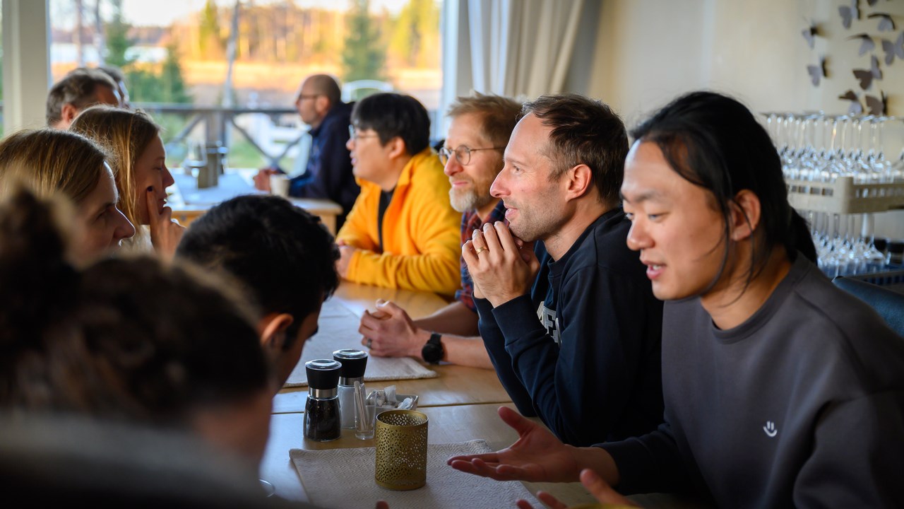 A group of people sitting at a table talking to each other