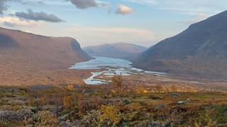 Vy över vattendrag genom fjällandskap.