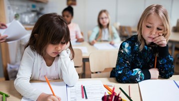 Lågstadieflickor jobbar i klassrum.