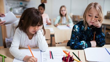 Lågstadieflickor jobbar i klassrum.