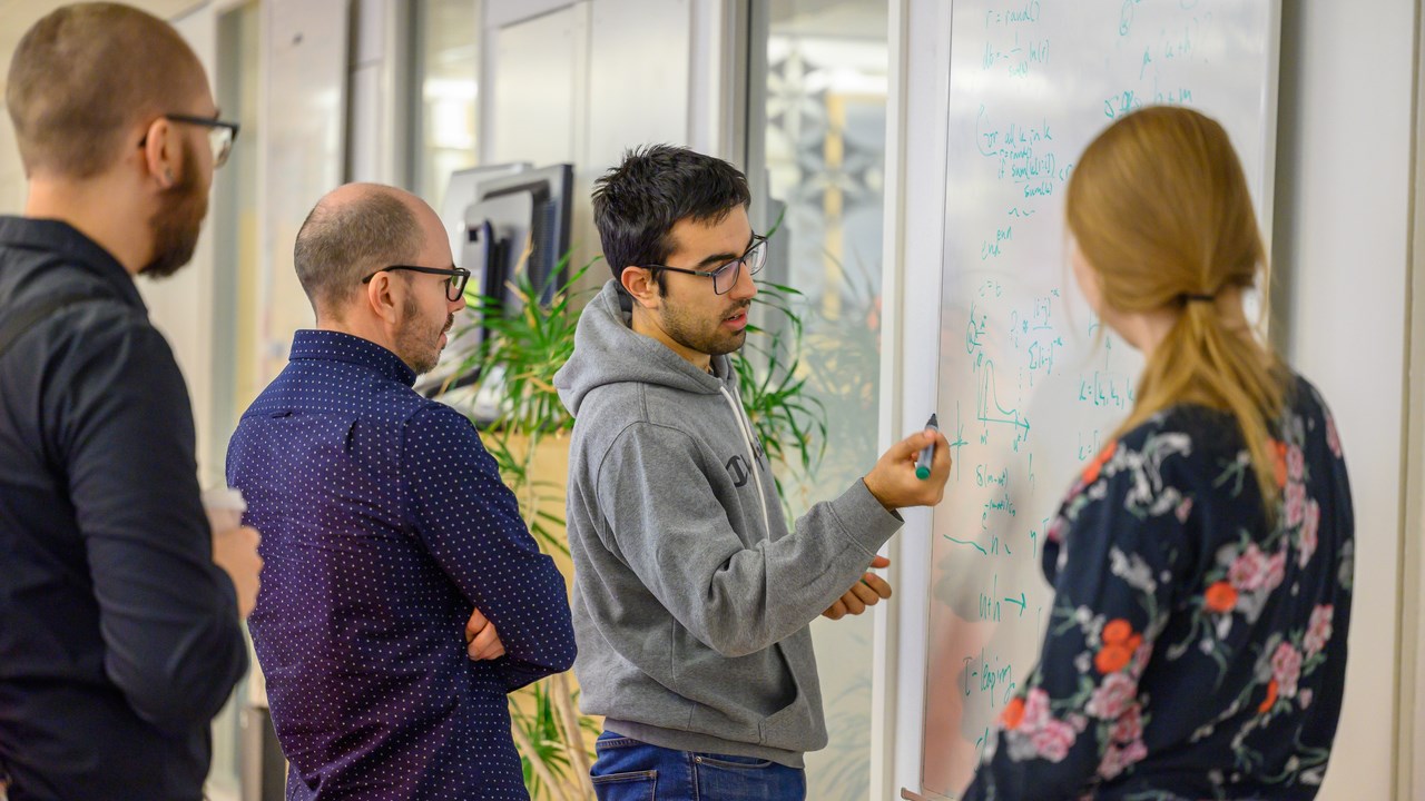 A group of people standing around a white board