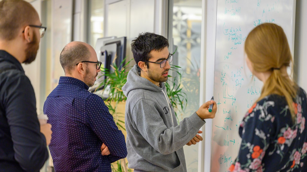 A group of people standing around a white board