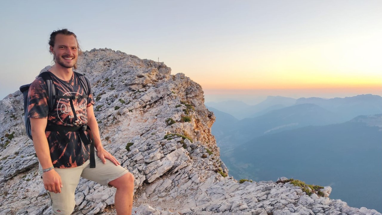 Bild på Michael Baumgärtner i halvfigur, stående på en stenig bergstopp.