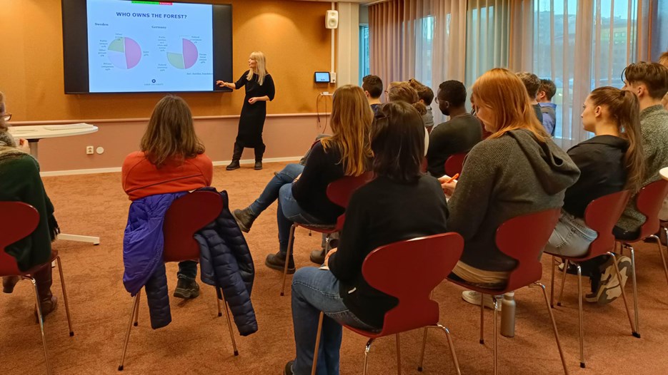 Janina Prebe står framför en publik och presenterar från en powerpoint.