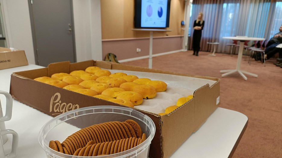 Lussebullar och pepparkakor i förgrund, presentation och publik i bakgrund