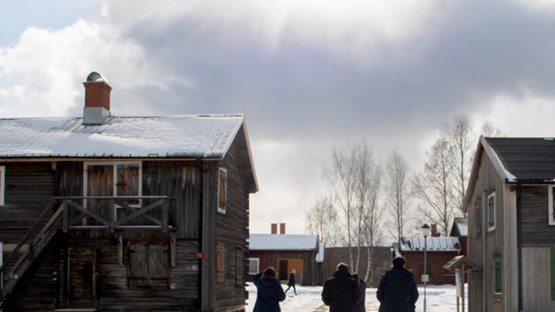 Grupp av människor som går på snö mellan två äldre byggnader