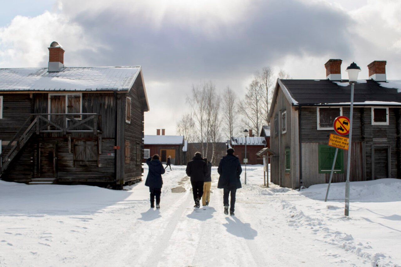 Grupp av människor som går på snö mellan två äldre byggnader