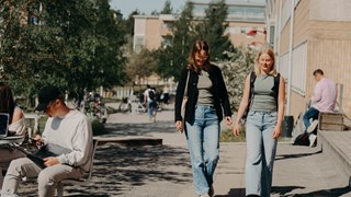Två kvinnor promenerar på campus. 
