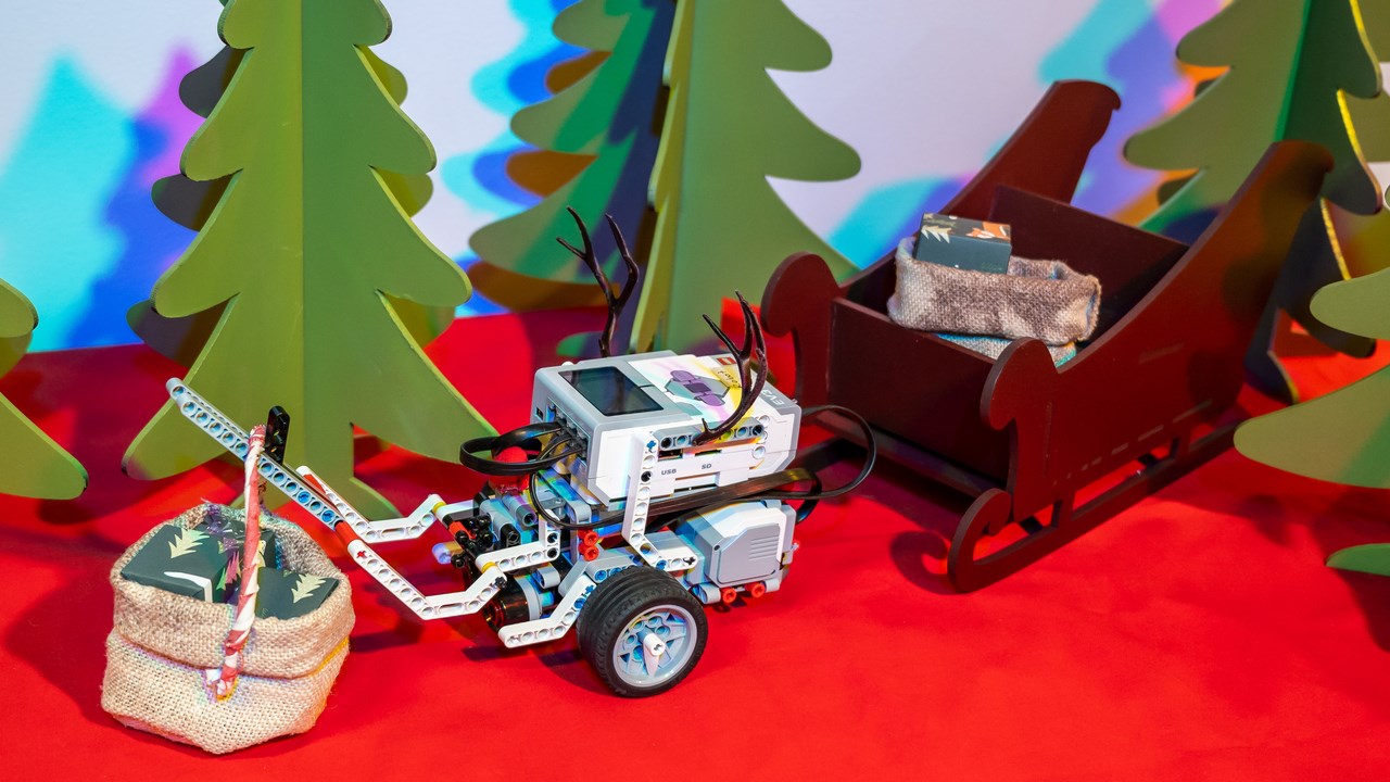 En EV3-robot med renhorn kör släde med julklappar bland granar