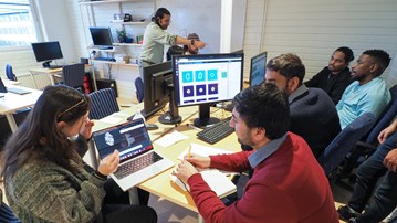 Students sitting by the computer discussing and looking at the screen with complex data visualised