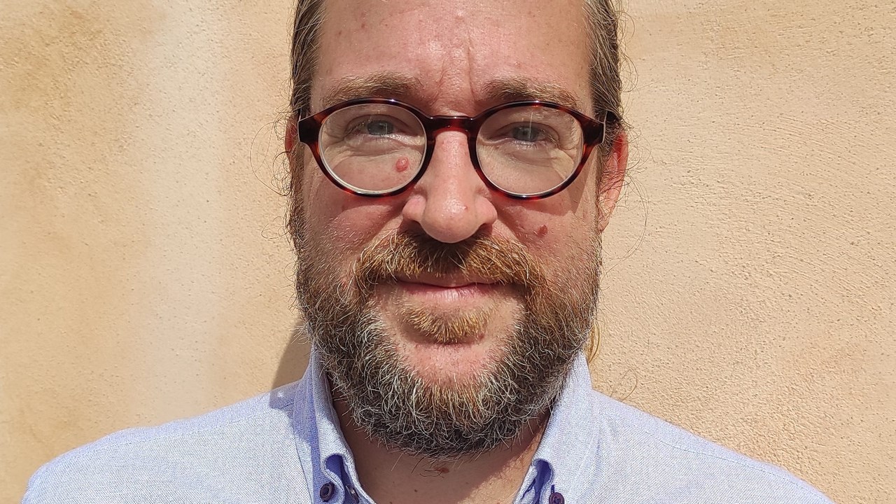 Man with glasses and a blue shirt smiling