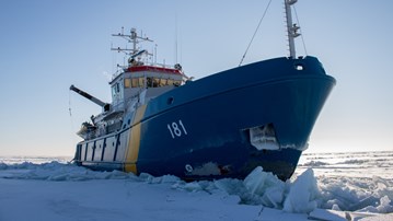 Ett stort blått fartyg märkt 181 stävar fram genom tjock is