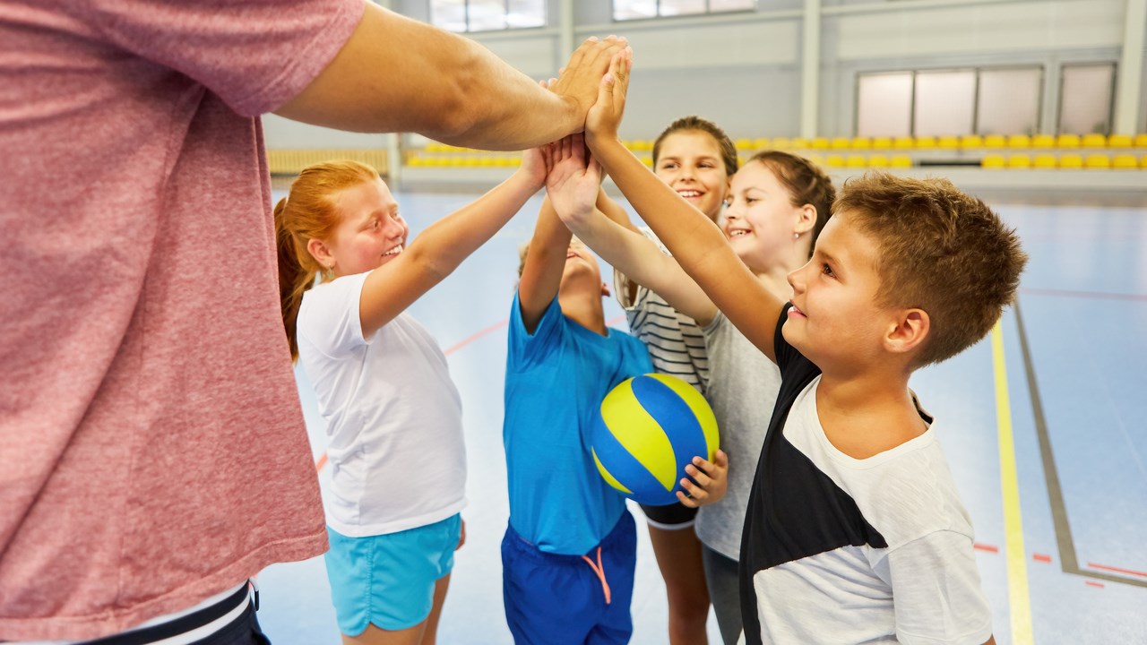 Children in a sports hall giving hive five