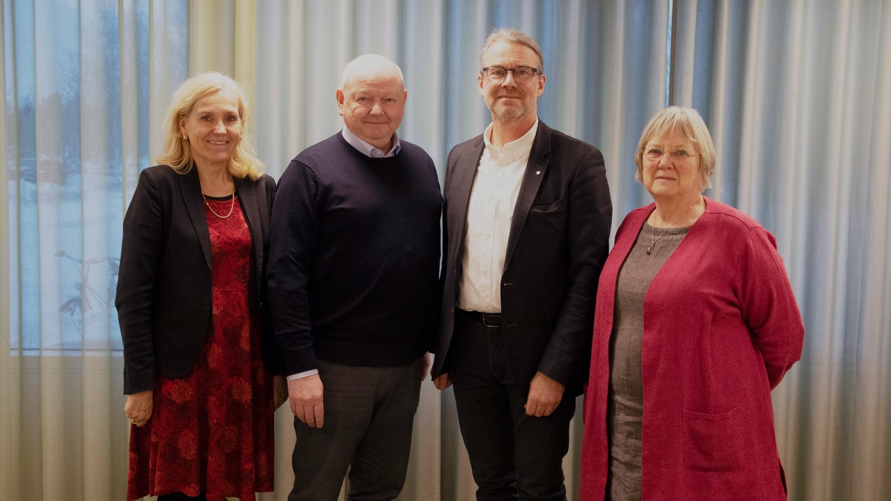 Fyra personer står axel mot axel och tittar in i kameran.