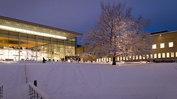 Vy över snötäckt Campus Umeå i skymningen i december.