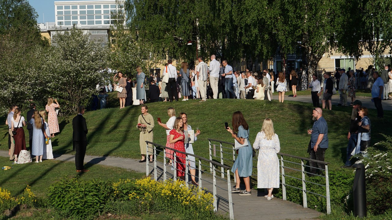 Studenter minglar utomhus i solen i samband med Handelshögskolans diplomeringsceremoni.