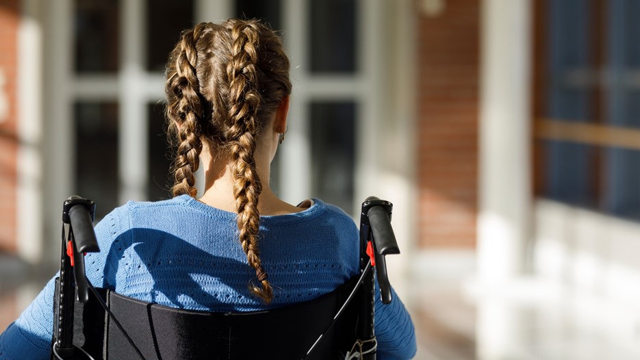 En flicka med flätor i håret sitter i en rullstol