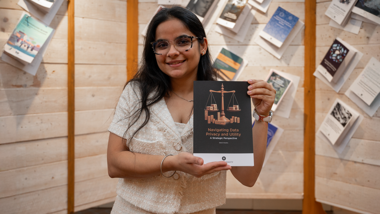 SK smiling at the camera holding her printed thesis.