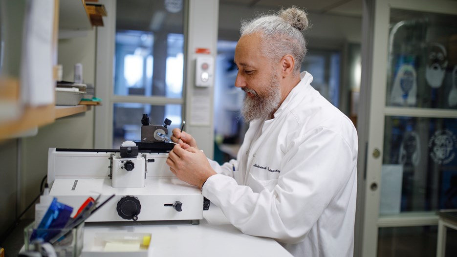 Matthew Marklund is standing by a microtome that he is using to section paraffin-embedded tissue.