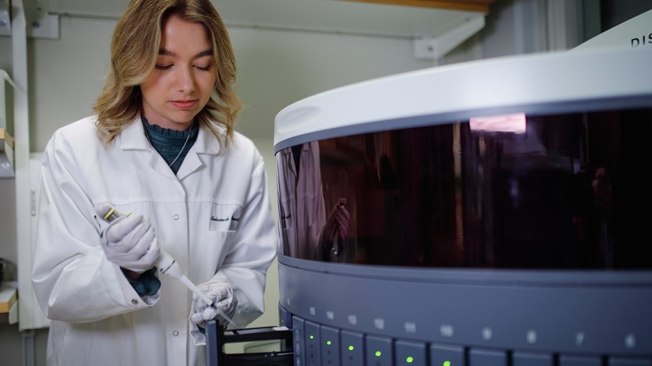 Isabelle Sigfridsson is pipetting antibody solution onto sectioned tissue samples mounted on a glass slide laying in an open cassette in an automated staining machine.