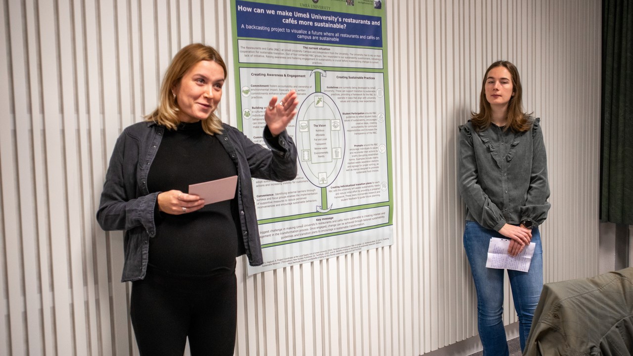 Bild på studenterna Agnes Alriksson och Rinske de Ronde stående vid sin posterpresentation.