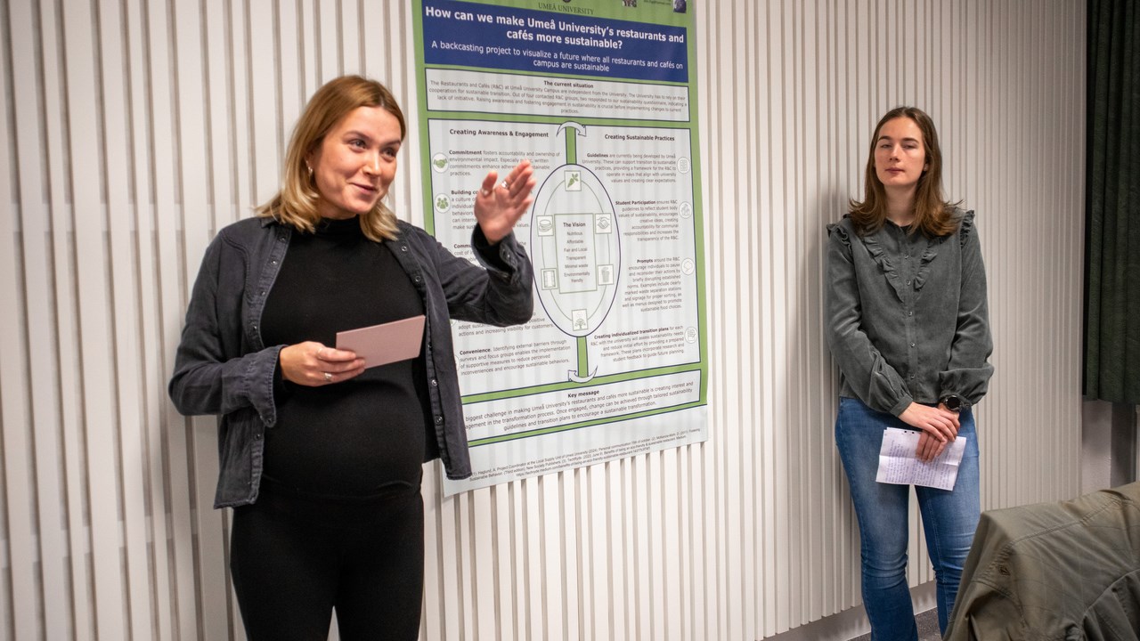 Bild på studenterna Agnes Alriksson och Rinske de Ronde stående vid sin posterpresentation.