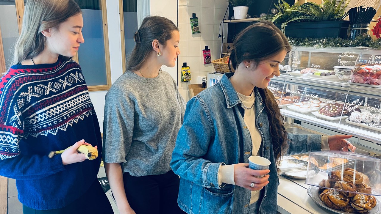 Bild på Elsa Nydén, Olivia Lundberg och Eira von Euler som pausar i pluggandet med att köpa fika i MIT-husets café Mitum.