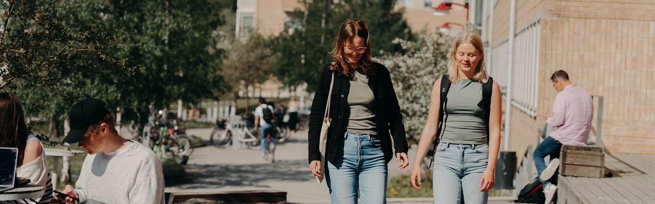Två kvinnor promenerar på campus. 