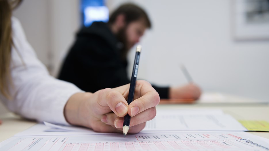 Studenter skriver prov i en tentasal.