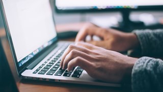 Two hands typing on a laptop.