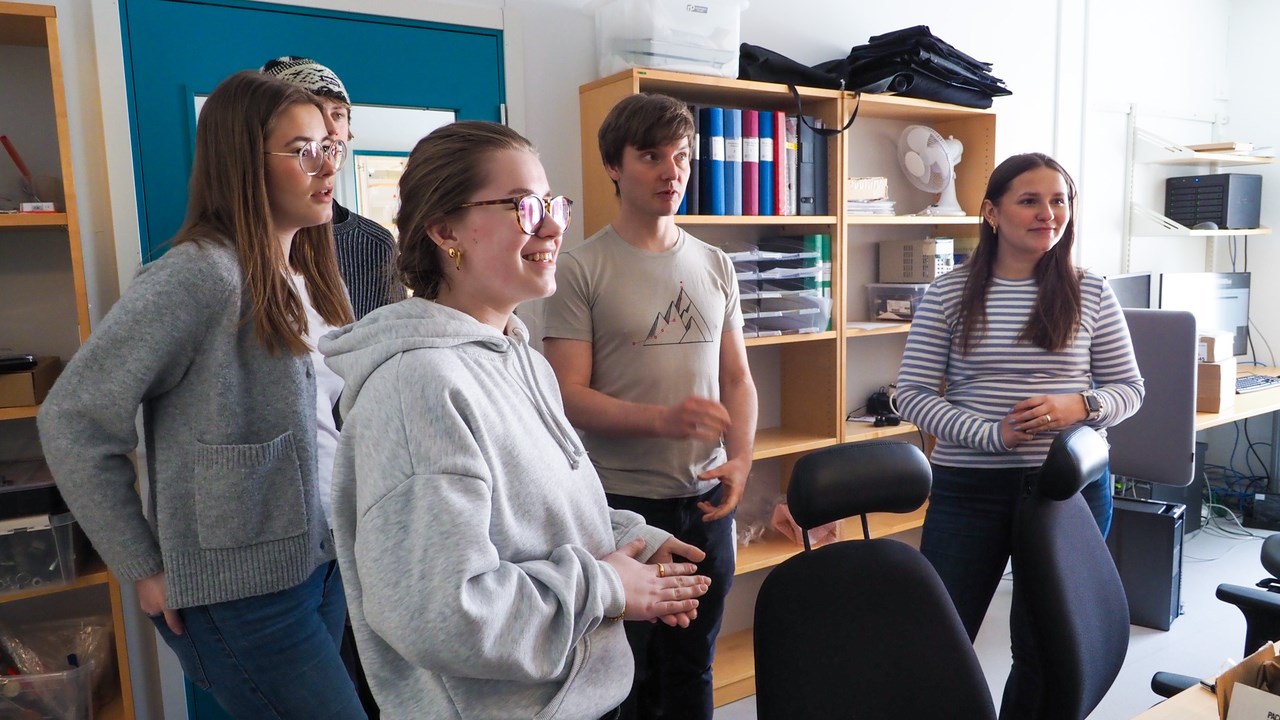 Nils Hauff,  staff scientists vid UCEM, visar eleverna Tilda Brännström Skilling, Rocky Andersson, Lovisa Wikman och Leona Stål det stora elektronmikroskopet vid UCEM.