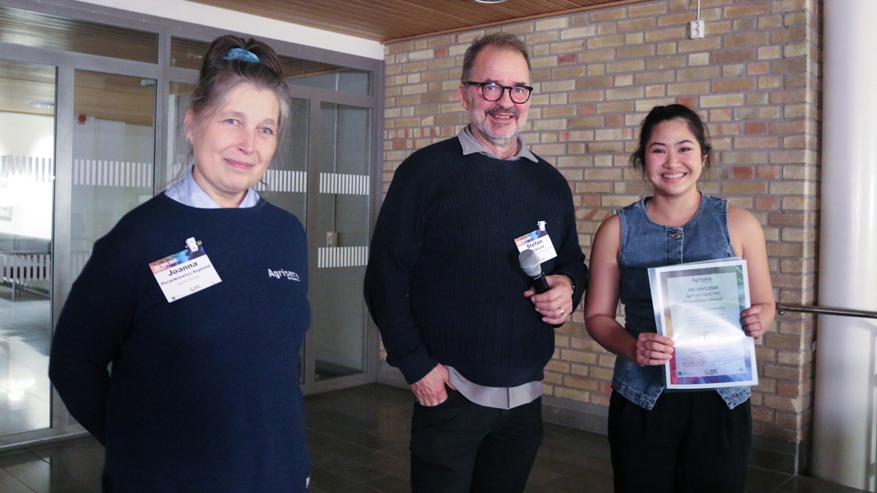 A female PhD student receiving award for the best presentation during the conference and is looking happy with the award certificate in her hands