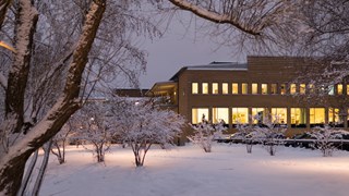 Vy över snötäckt Campus Umeå i skymningen i december.