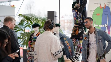 Students wearing student overalls talking to visitors at a Student Fair in Lindell hall, Umeå University. 