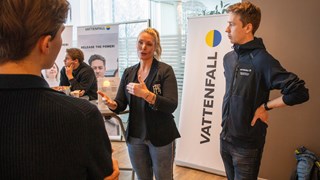 Bild på Frida Häggström och Jakob Backman, Vattenfall, i samtal med student. I bakgrunden Vattenfalls rollup.