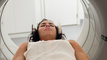 Kvinna med hörlurar ligger i MR-kamera