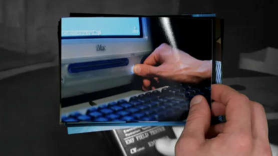 En hand som håller i ett foto av en hand som trycker på en gammal dator.
