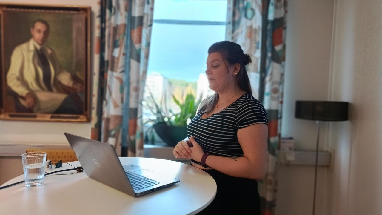 Rebecca Tapper står vid en laptop och presenterar sitt forskningsprojekt