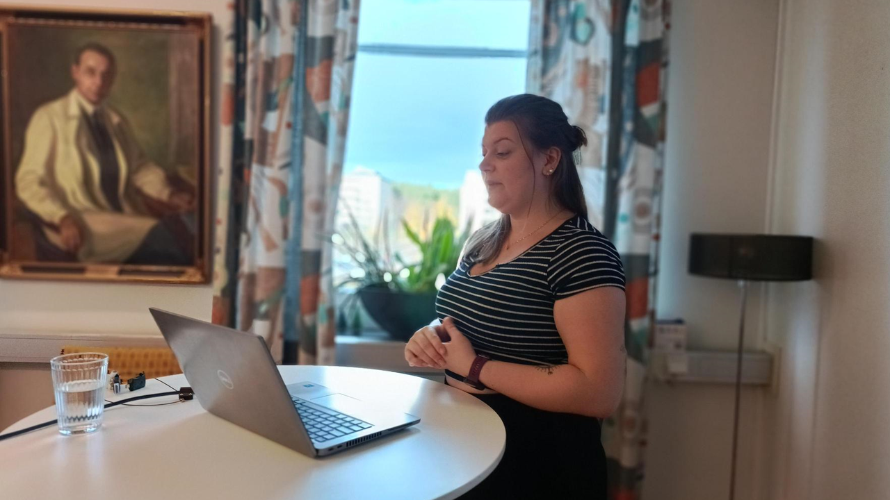 Rebecca Tapper står vid en laptop och presenterar sitt forskningsprojekt