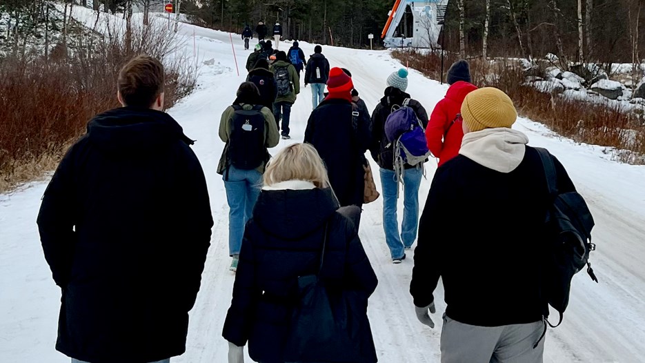 Personer vandrar längs en uppförsbacke i snölandskap