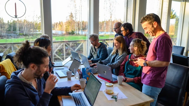 A group of people sitting at a table with laptops