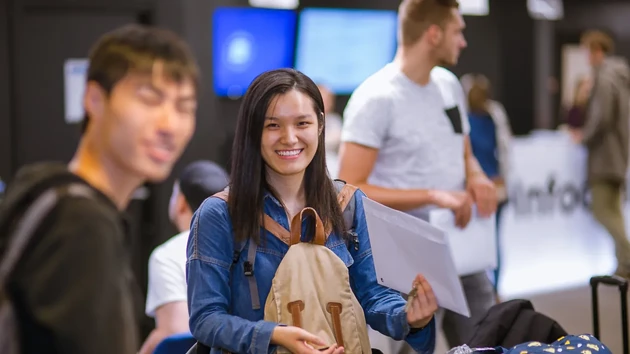 Utbytesstudent håller i kuvert, nycklar och ryggsäck på ankomstdagen